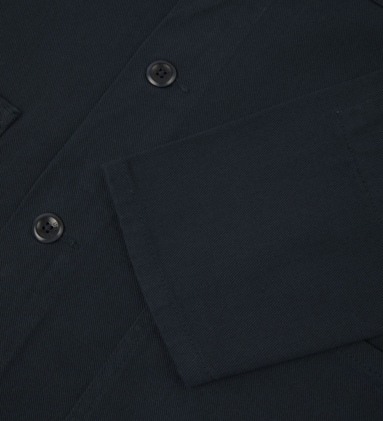 View of the mid-section and sleeve of the 3001 Uskees button-down drill overshirt in dark blue (blueberry) with focus on cuff, placket and hip pocket.