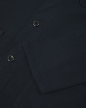 View of the mid-section and sleeve of the 3001 Uskees button-down drill overshirt in dark blue (blueberry) with focus on cuff, placket and hip pocket.