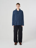 Full-length view of man wearing an Uskees blueberry ripstop overshirt paired with dark pants.