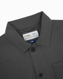 Close-up top-half view of #3001, charcoal-grey organic cotton drill overshirt. With focus on collar, Uskees brand label and corozo buttons.