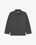 Front flat shot of charcoal-grey, buttoned drill overshirt. Clear view of corozo buttons, 3 pockets and Uskees branding label.