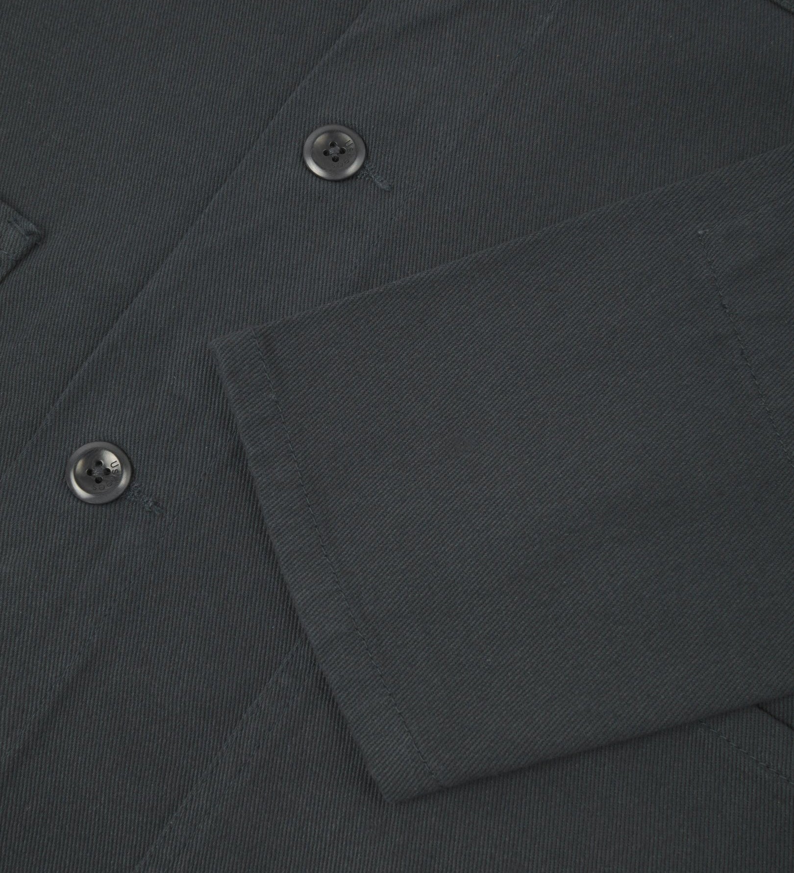 View of the mid-section and sleeve of the 3001 Uskees button-down drill overshirt in charcoal-grey with focus on cuff, placket and hip pocket.