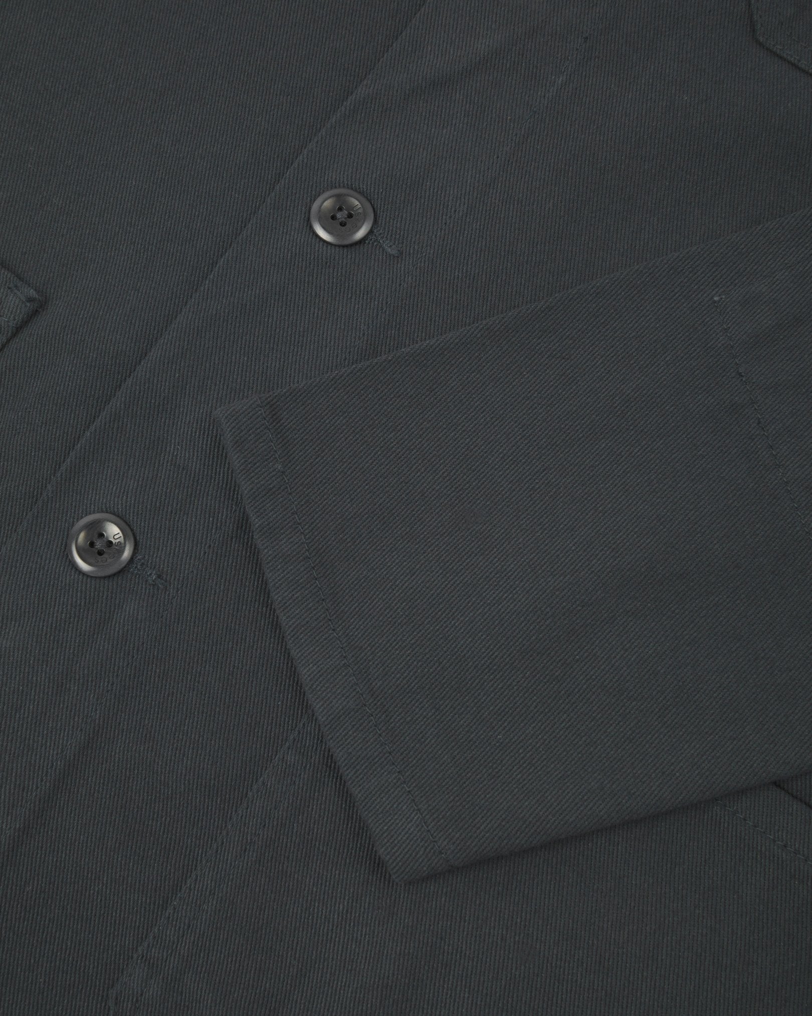 View of the mid-section and sleeve of the 3001 Uskees button-down drill overshirt in charcoal-grey with focus on cuff, placket and hip pocket.