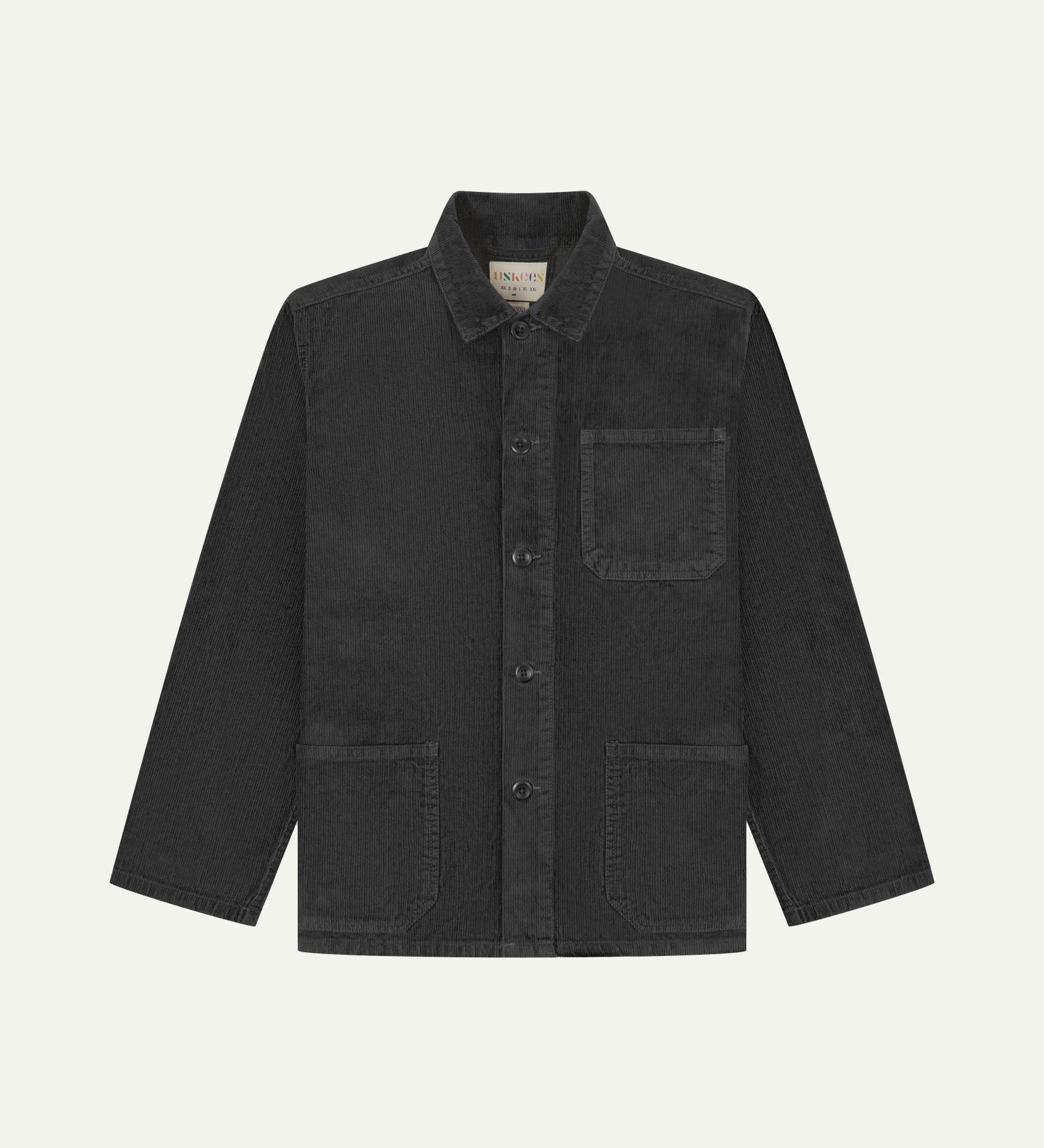 Front flat shot of charcoal-grey, buttoned corduroy overshirt. Clear view of chest and hip pockets, corozo buttons and Uskees branding label.