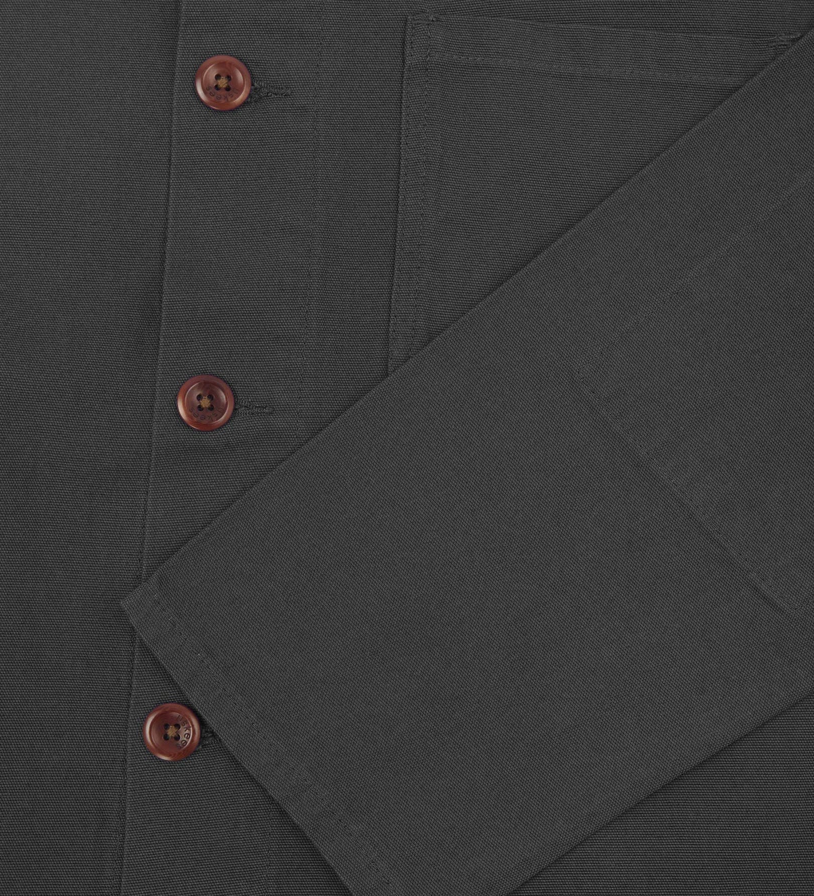 Closer view of mid section of charcoal-grey, buttoned organic cotton overshirt from Uskees. Focus on cuff, pockets and corozo buttons.