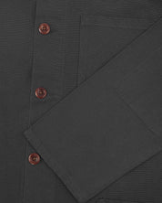 Closer view of mid section of charcoal-grey, buttoned organic cotton overshirt from Uskees. Focus on cuff, pockets and corozo buttons.