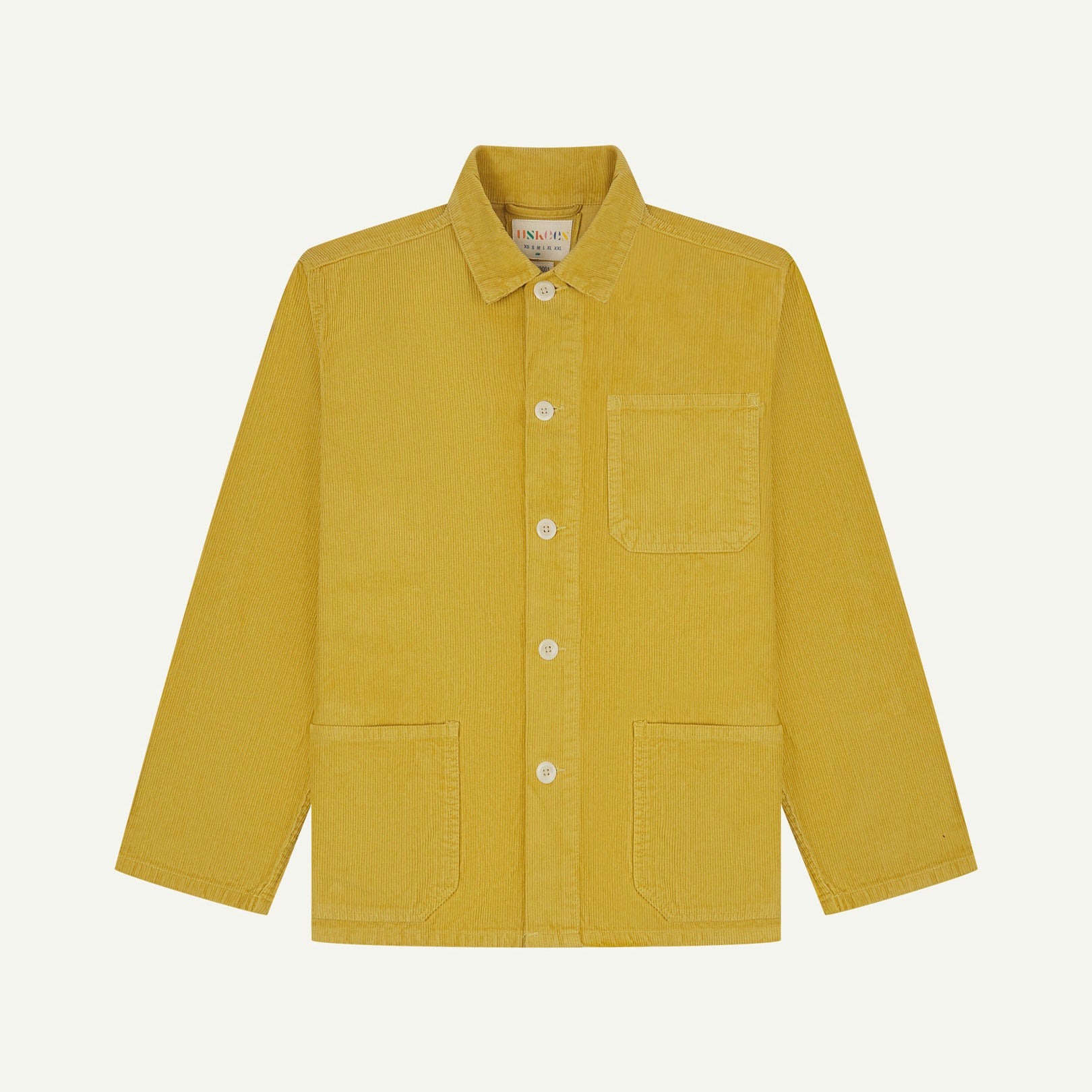 Front flat shot of yellow (citronella), buttoned corduroy overshirt. Clear view of chest and hip pockets, corozo buttons and Uskees branding label.