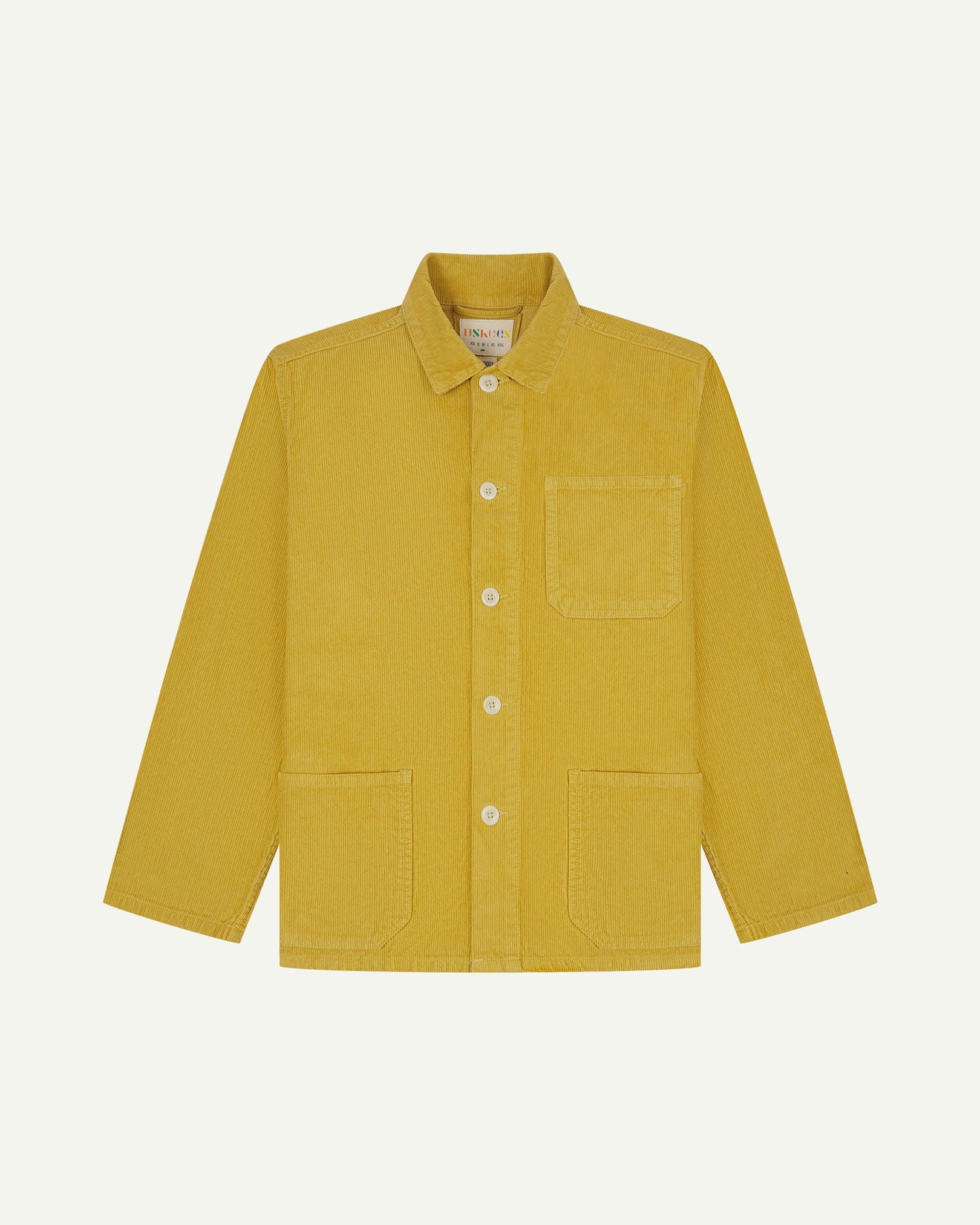 Front flat shot of yellow (citronella), buttoned corduroy overshirt. Clear view of chest and hip pockets, corozo buttons and Uskees branding label.