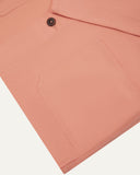 Closer view of mid section of pink-orange (coral), buttoned organic cotton overshirt from Uskees. Focus on cuff, pockets and corozo buttons.