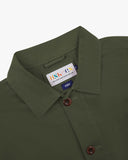 Close-up view of 3001 coriander-green, buttoned organic cotton overshirt from Uskees showing corozo buttons, brand label, collar and hanging hoop.