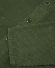 Closer view of mid section of coriander-green, buttoned corduroy overshirt from Uskees. Focus on cuff, pockets, corozo buttons and corduroy texture.