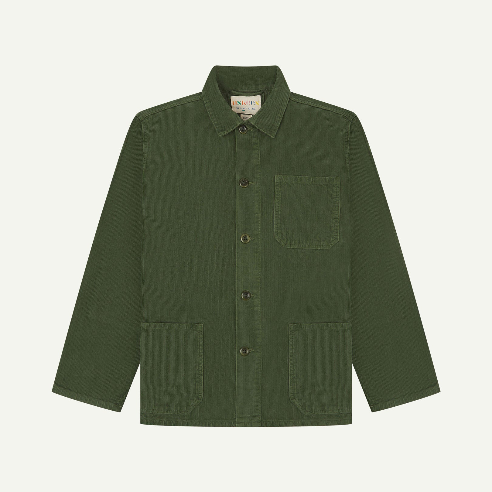 Front flat shot of coriander-green, buttoned corduroy overshirt. Clear view of chest and hip pockets, corozo buttons and Uskees branding label.