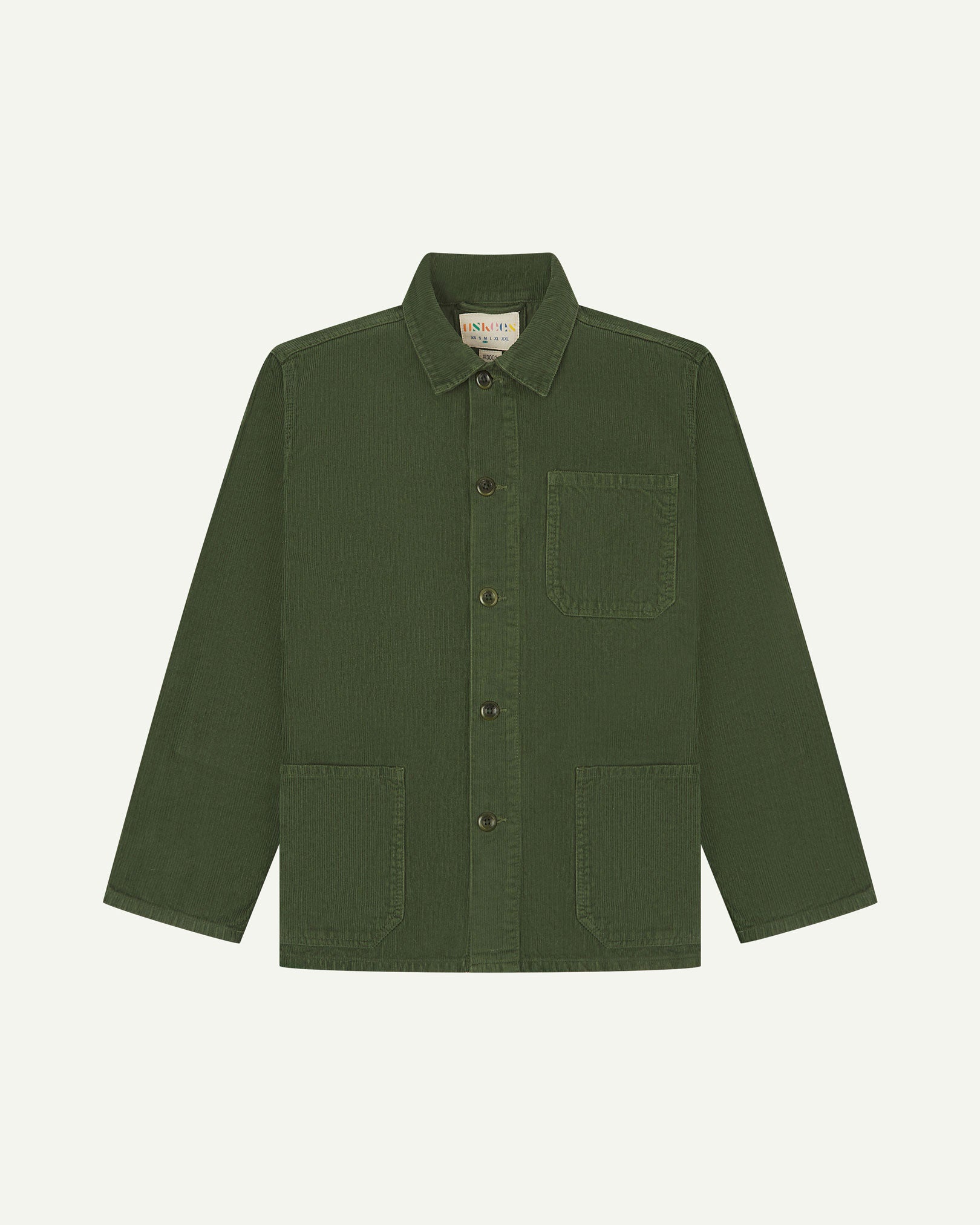 Front flat shot of coriander-green, buttoned corduroy overshirt. Clear view of chest and hip pockets, corozo buttons and Uskees branding label.