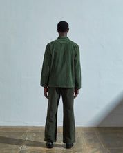 Full-length reverse view of model wearing  #3001, coriander-green corduroy overshirt with view of reinforced elbow area and demonstrating boxy silhouette.