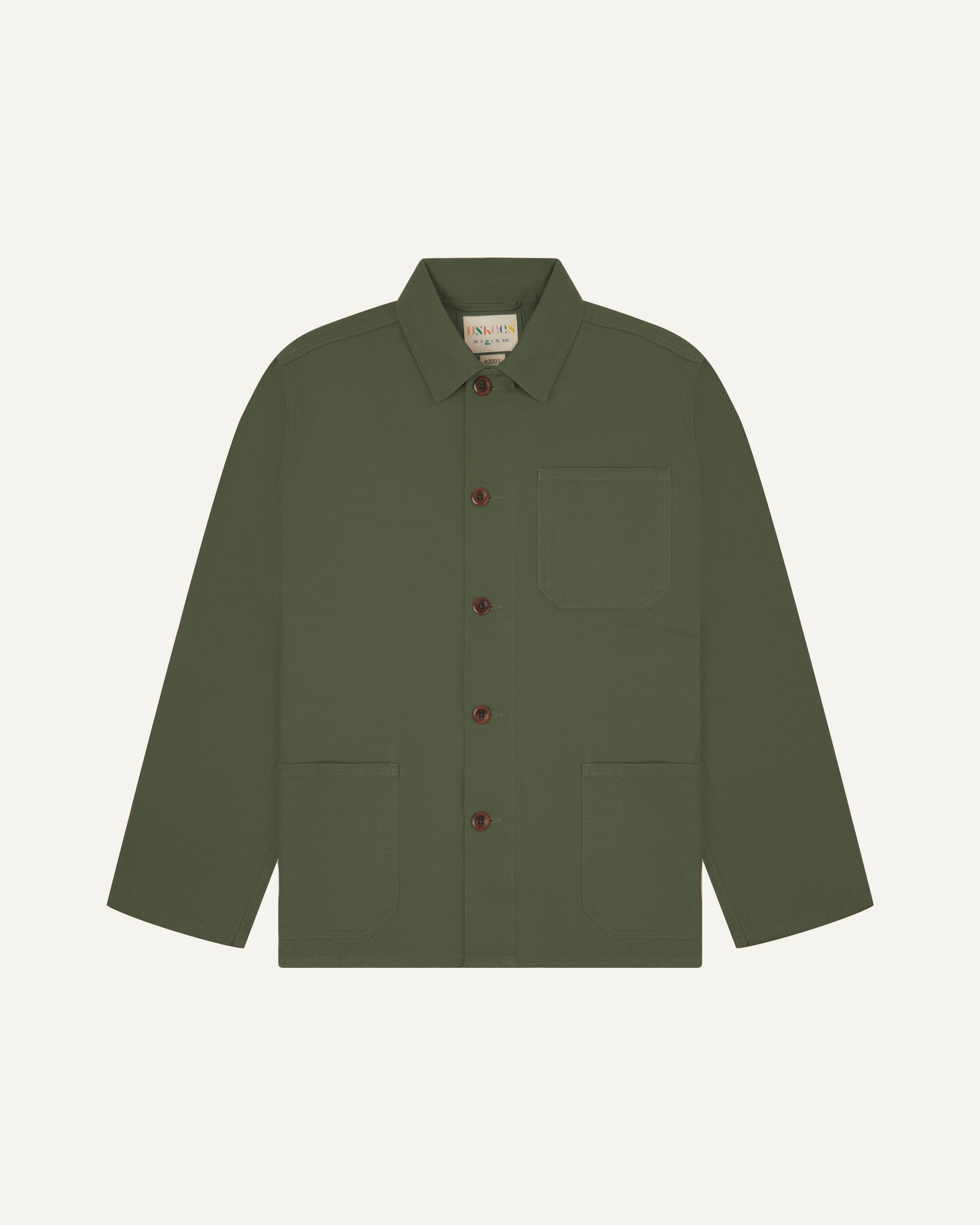 Front flat shot of coriander-green, buttoned organic cotton overshirt. Clear view of chest and hip pockets, corozo buttons and Uskees branding label.