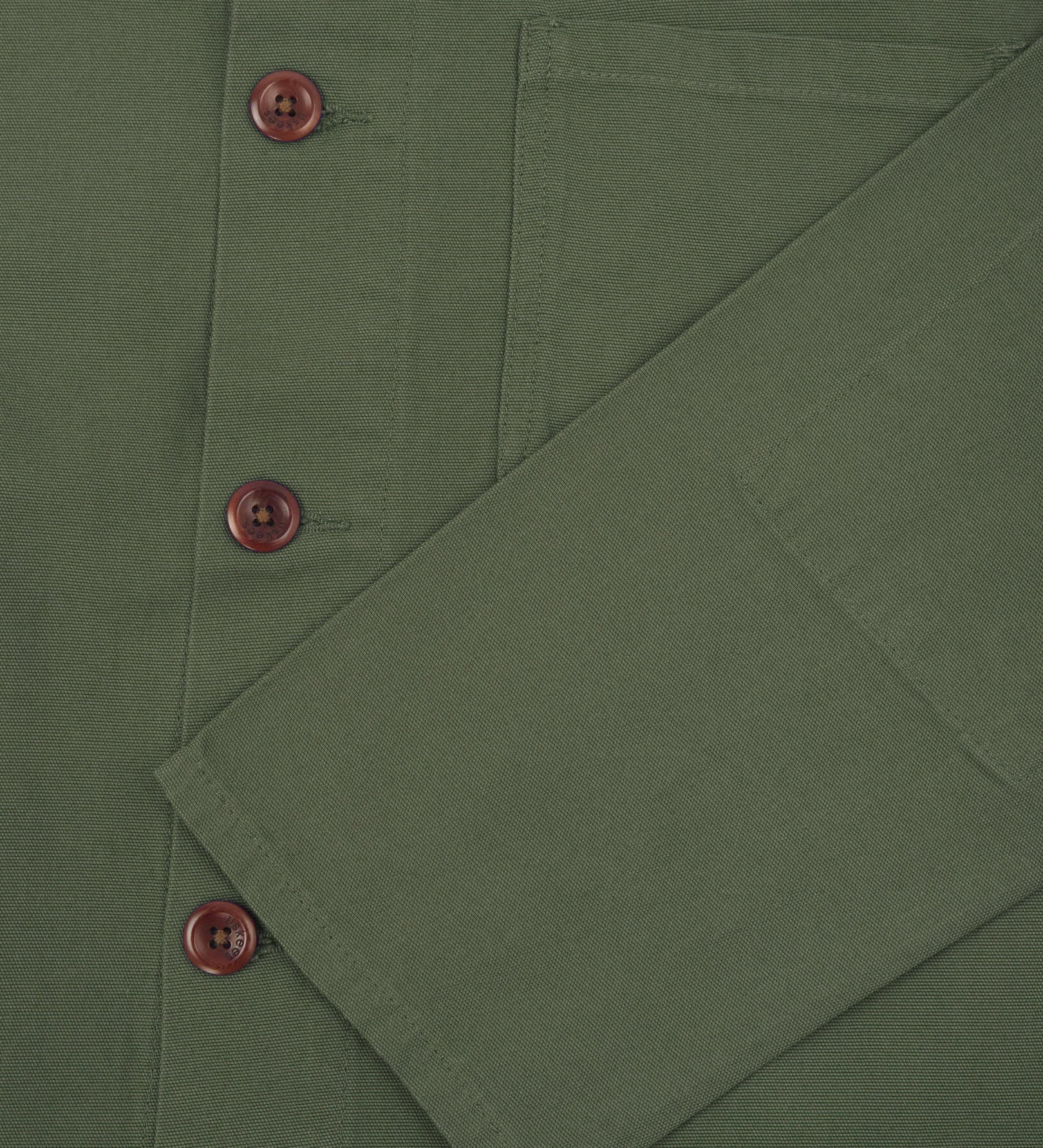 Closer view of mid section of coriander-green, buttoned organic cotton overshirt from Uskees. Focus on cuff, pockets and corozo buttons.