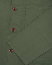 Closer view of mid section of coriander-green, buttoned organic cotton overshirt from Uskees. Focus on cuff, pockets and corozo buttons.