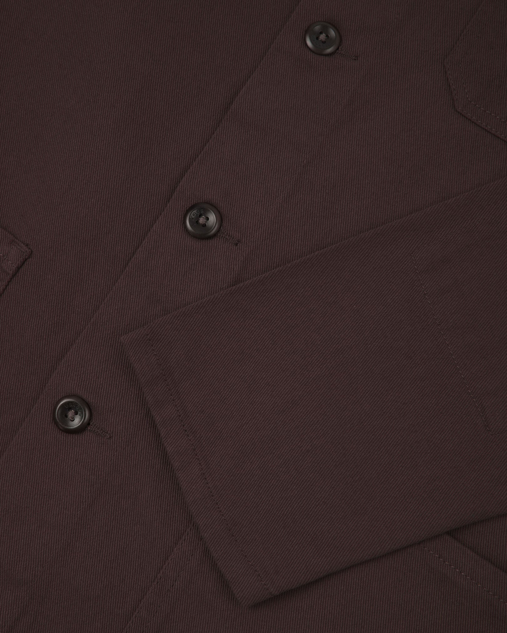 View of the mid-section and sleeve of the 3001 Uskees button-down drill overshirt in burgundy-brown with focus on cuff, placket and hip pocket.