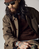 Male model wearing sunglasses, an Uskees dark taupe shacket and loam brown sweater against a plain background