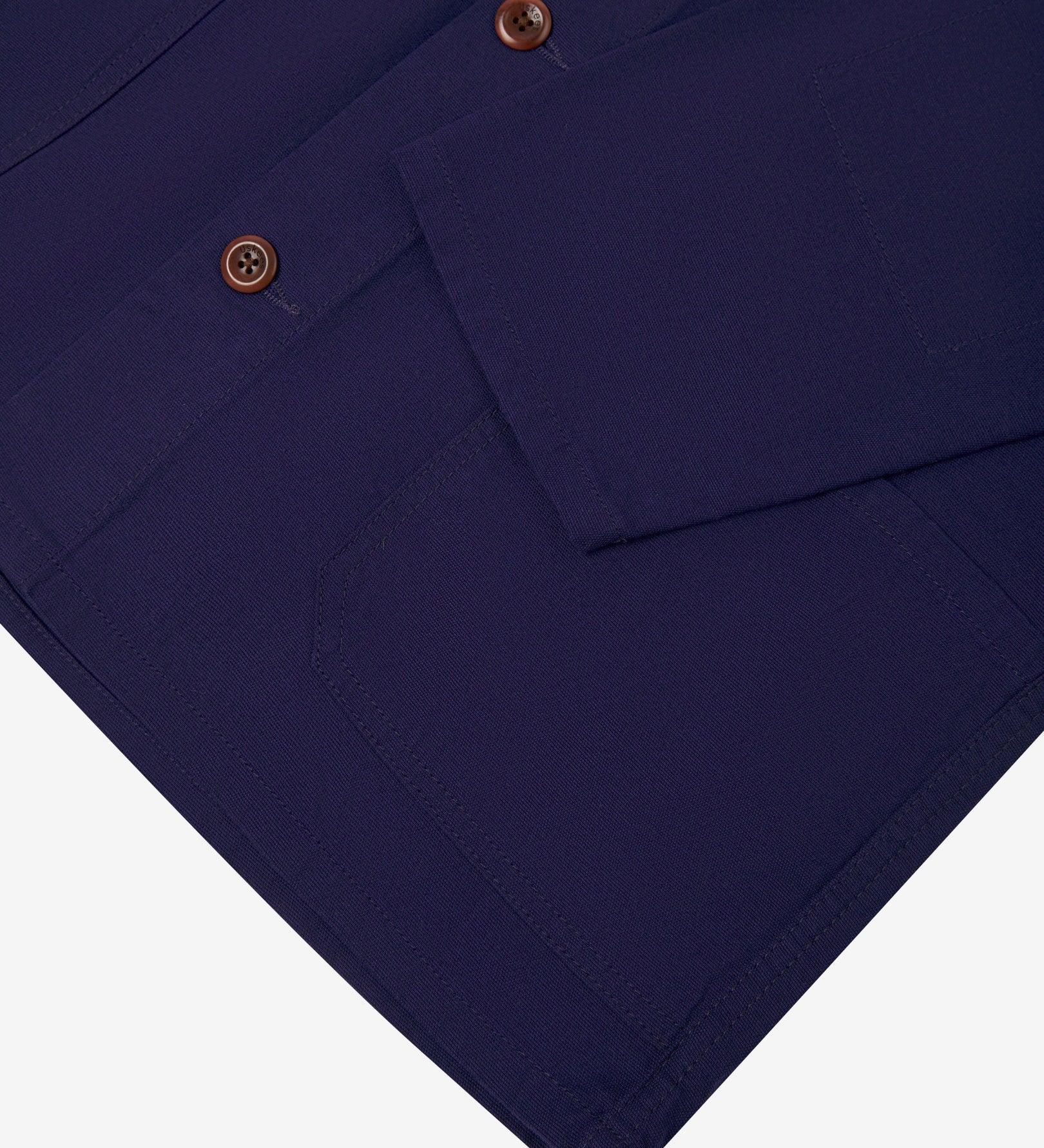 Closer view of deep indigo, buttoned organic cotton overshirt from Uskees. Focus on cuff, placket, hip pocket and corozo buttons.