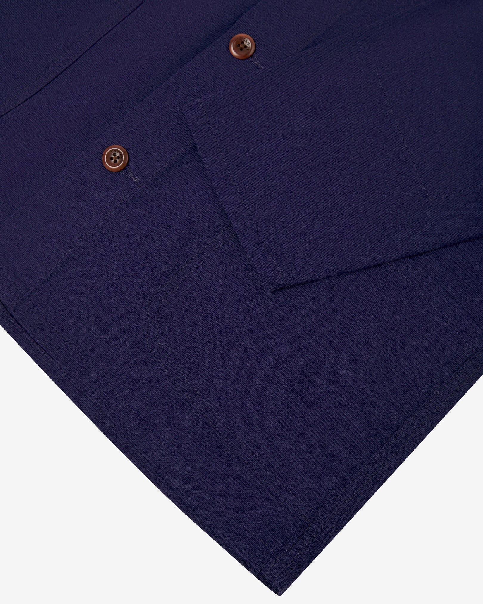 Closer view of deep indigo, buttoned organic cotton overshirt from Uskees. Focus on cuff, placket, hip pocket and corozo buttons.