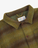 Close-up view of 3001 woodland green check, buttoned Pennine wool overshirt from Uskees showing corozo buttons, brand/size label, collar and hanging hoop.