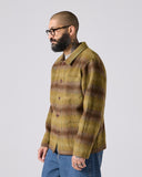 Model wearing Delph woodland green check, buttoned Pennine wool overshirt. Showing side and paired with jeans.