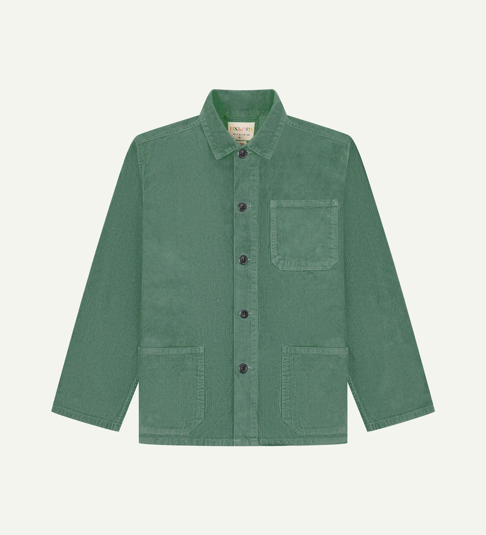 Front flat shot of light green, buttoned corduroy overshirt. Clear view of chest and hip pockets, corozo buttons and Uskees branding label.
