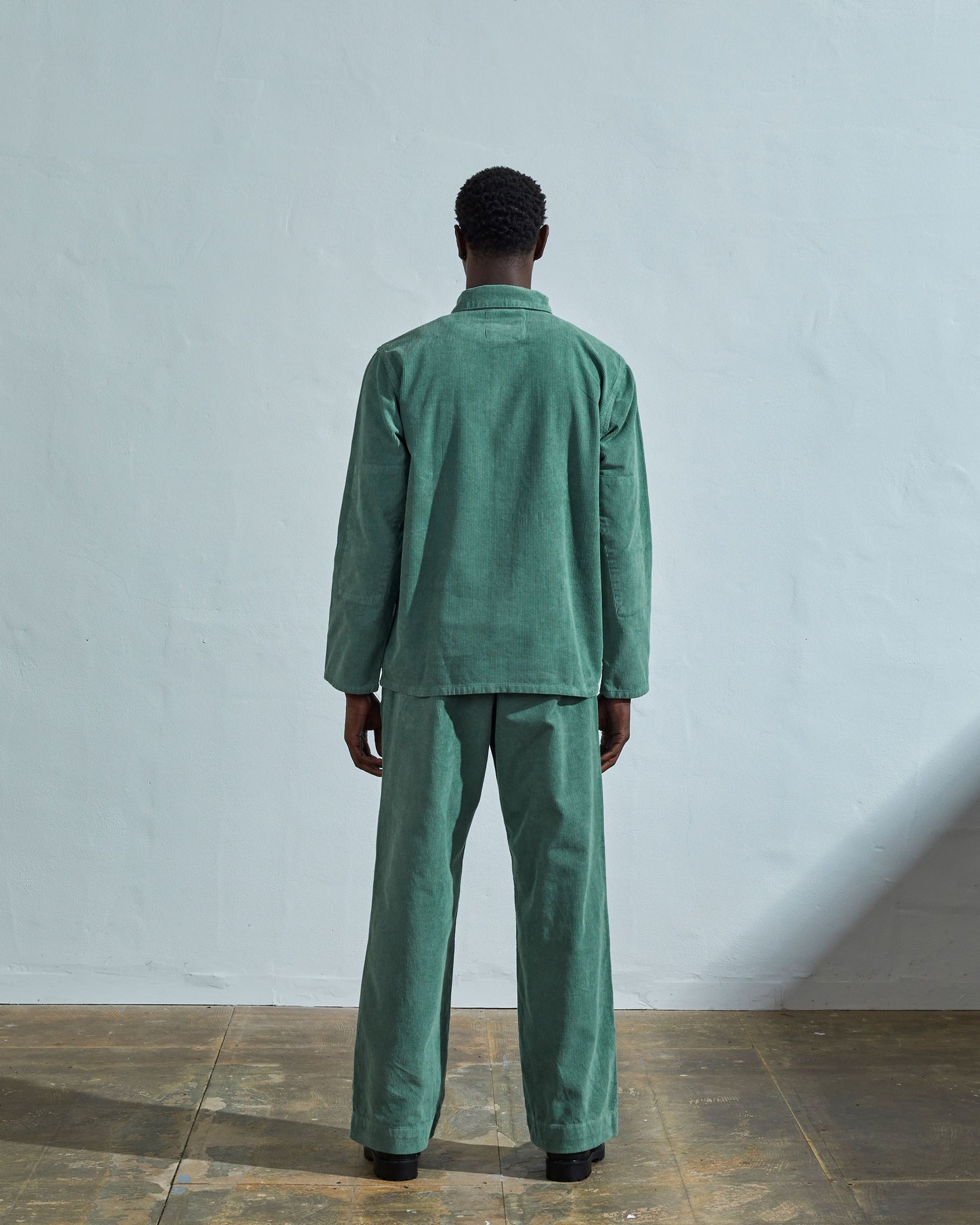 Full-length reverse view of model wearing #3001, eucalyptus corduroy overshirt paired with matching Uskees eucalyptus-green cord pants.