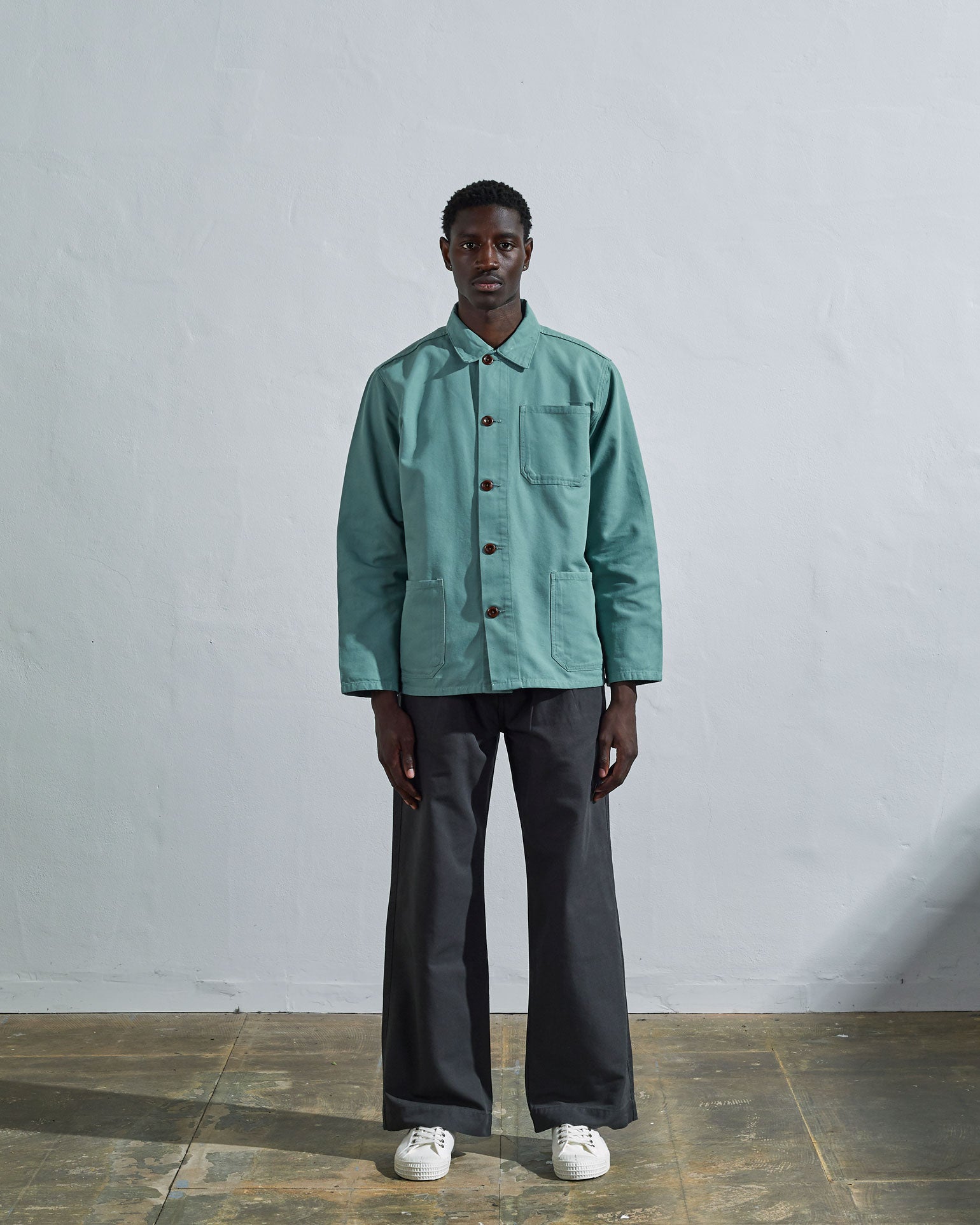 Full-length front view of model wearing #3001, blue-green 'eucalyptus' organic cotton overshirt paired with dark pants.