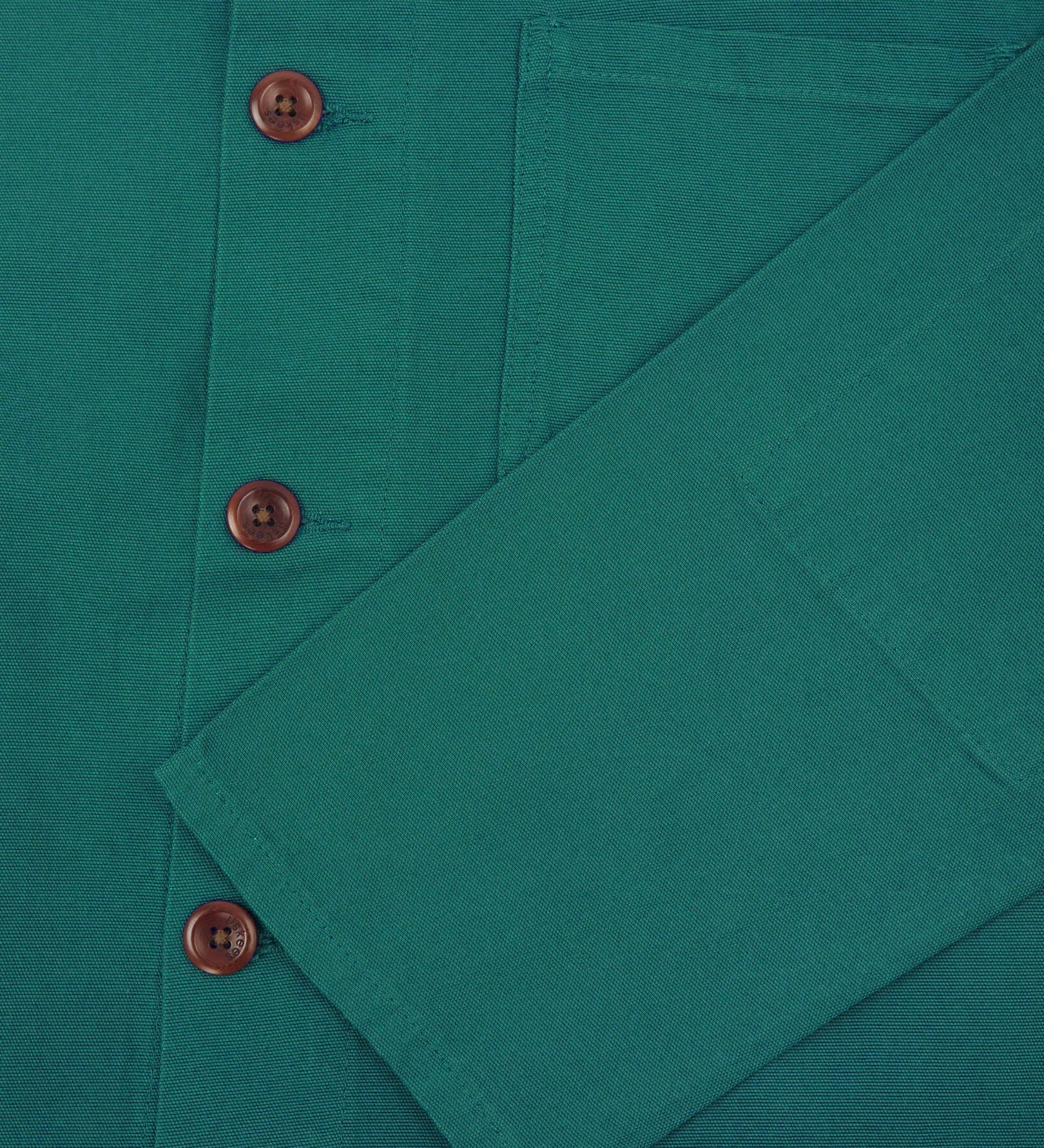 Closer view of mid section of foam green, buttoned organic cotton overshirt from Uskees. Focus on cuff, pockets and corozo buttons.