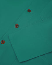 Closer view of mid section of foam green, buttoned organic cotton overshirt from Uskees. Focus on cuff, pockets and corozo buttons.