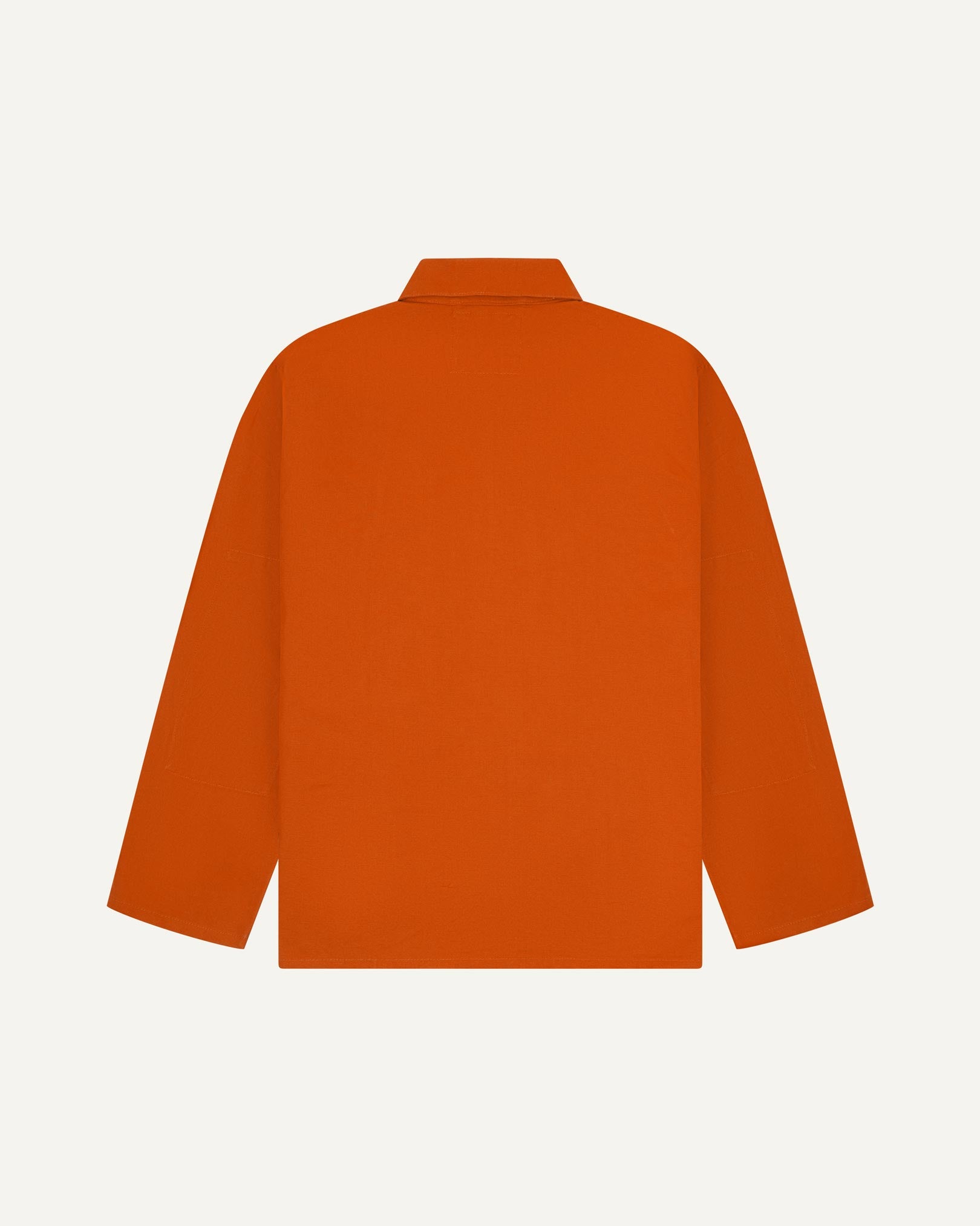 Back view of golden-orange, buttoned organic cotton overshirt with view of reinforced elbow area and boxy silhouette.
