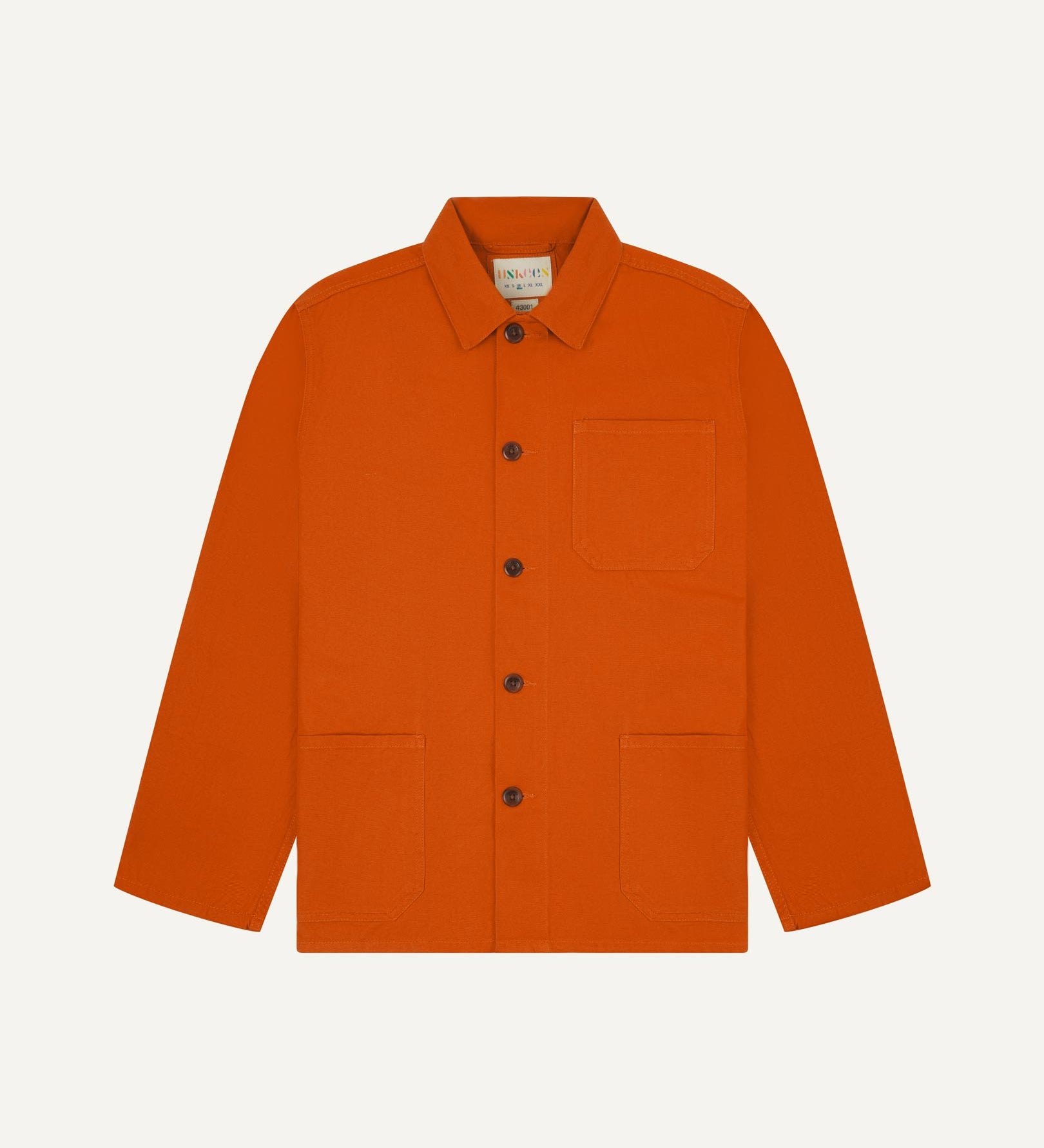 Front flat shot of golden-orange, buttoned organic cotton overshirt. Clear view of chest and hip pockets, corozo buttons and Uskees branding label.