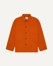 Front flat shot of golden-orange, buttoned organic cotton overshirt. Clear view of chest and hip pockets, corozo buttons and Uskees branding label.