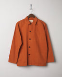 Golden orange buttoned organic cotton overshirt from Uskees presented on hanger. Clear view of breast and hip pocket and corozo buttons.