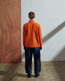 Full-length rear view of model wearing #3001, gold-orange organic cotton over shirt with reinforced elbows.