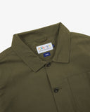 Close-up view of 3001 olive green, buttoned ripstop overshirt from Uskees showing corozo buttons, brand label, collar and hanging hoop.