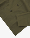 Closer view bottom-right section of olive green, buttoned ripstop overshirt from Uskees. Focus on cuff, pockets and corozo buttons.