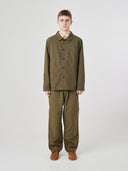 Full-length view of man wearing an Uskees olive green ripstop overshirt paired with matching pants.