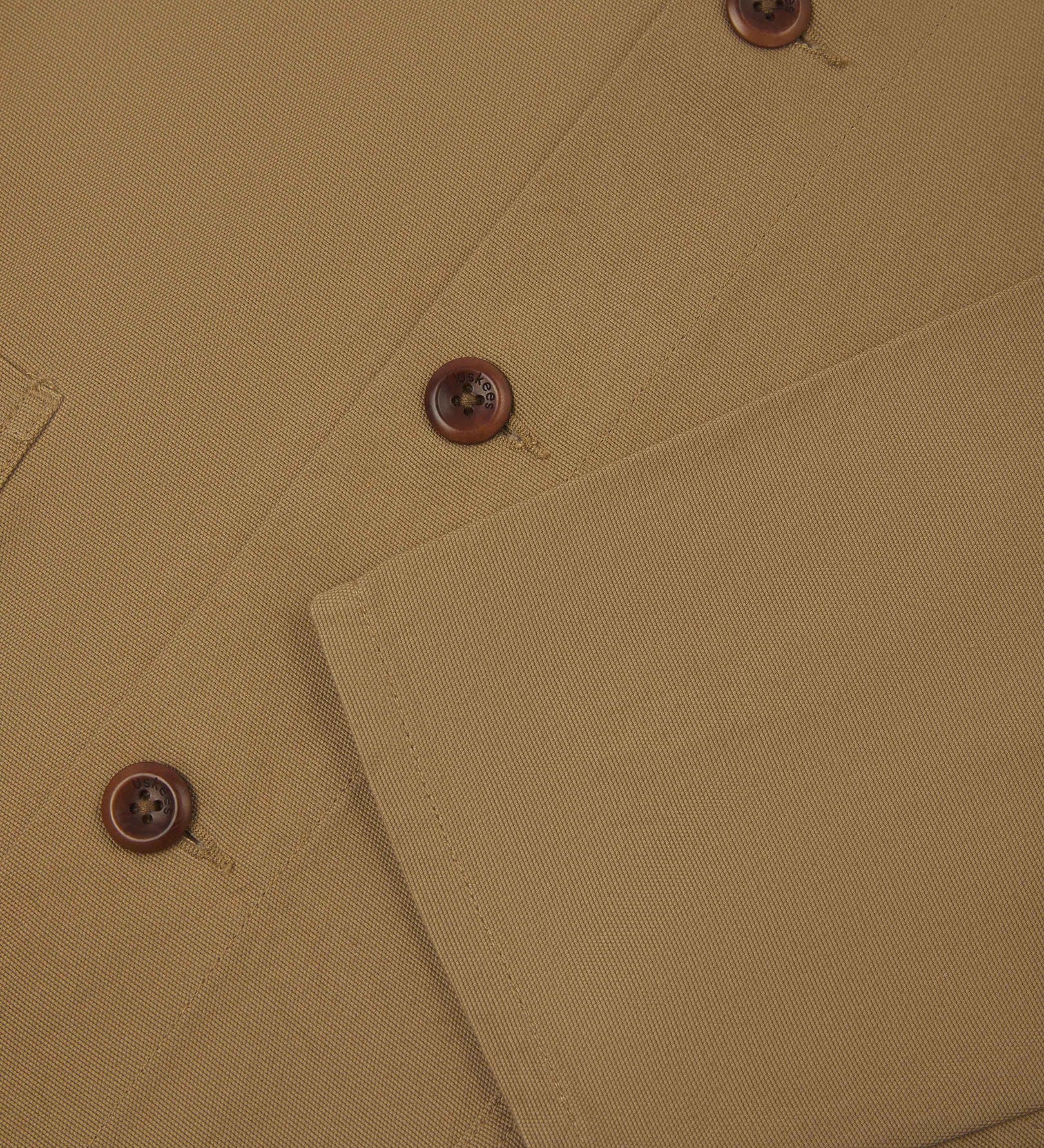 Closer view of mid section of khaki, buttoned organic cotton overshirt from Uskees. Focus on cuff, pockets and corozo buttons.
