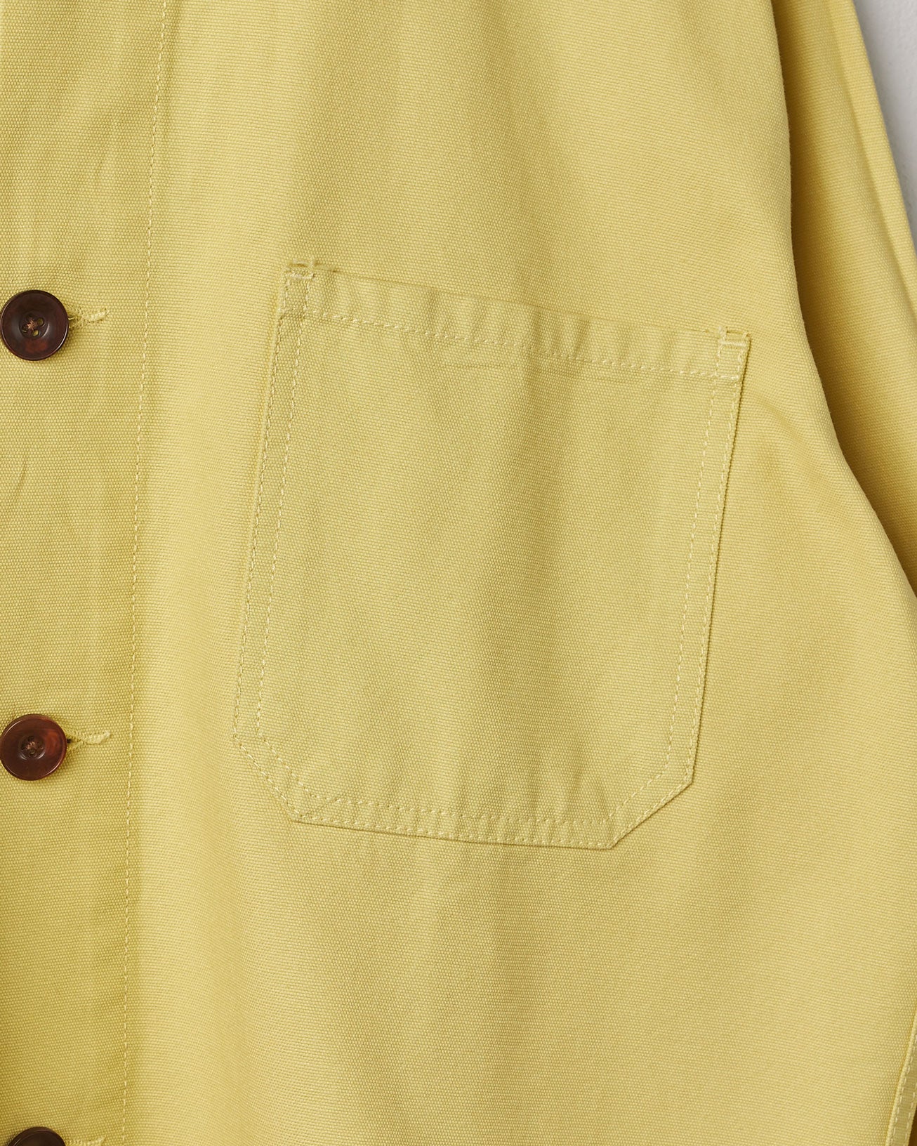 Close-up, mid view of 'lime' organic cotton overshirt from Uskees with clear view of dark corozo buttons and breast pocket.