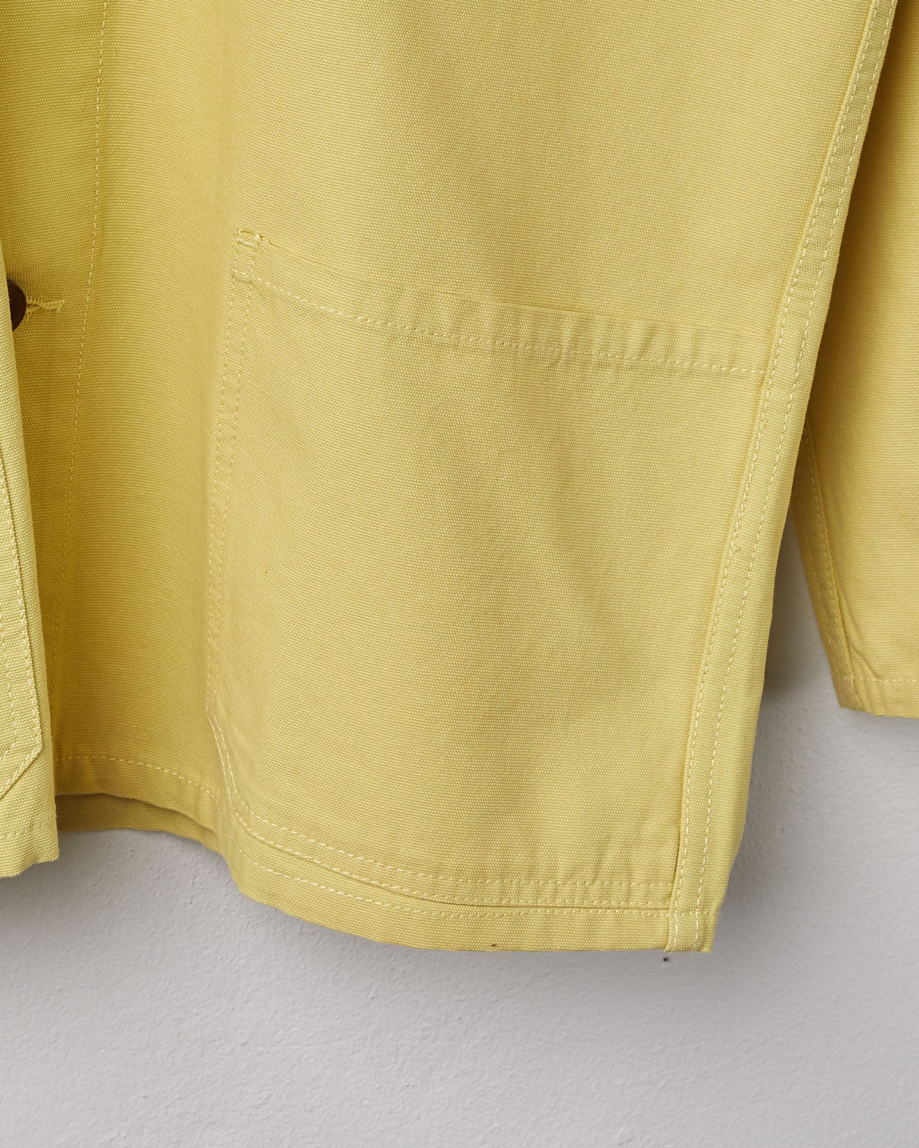 Close-up, bottom-left view of lime-coloured organic cotton overshirt from Uskees with clear view of left hip pocket and sleeve.