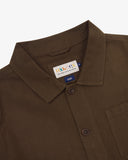 Close-up top-half view of #3001 brown linen blend overshirt. With focus on collar, Uskees brand label and corozo buttons.