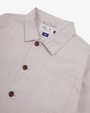 Close-up top-half view of #3001 lunar stone (light grey) organic cotton organic cotton overshirt. With focus on collar, Uskees brand label and corozo buttons.