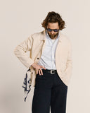 Top-half view modelling 3001 Uskees men's linen blend off-white linen blend overshirt. Paired with blue and white pinstripe Uskees shirt.