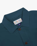 Close-up top-half view of #3001 maya blue organic cotton organic cotton overshirt. With focus on collar, Uskees brand label and corozo buttons.