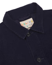 Close-up view of 3001 midnight blue, buttoned corduroy overshirt from Uskees showing corozo buttons, brand/size label, collar and hanging hoop.