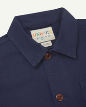 Close up shot of midnight blue overshirt showing collar, front buttons and uskees brand/size label