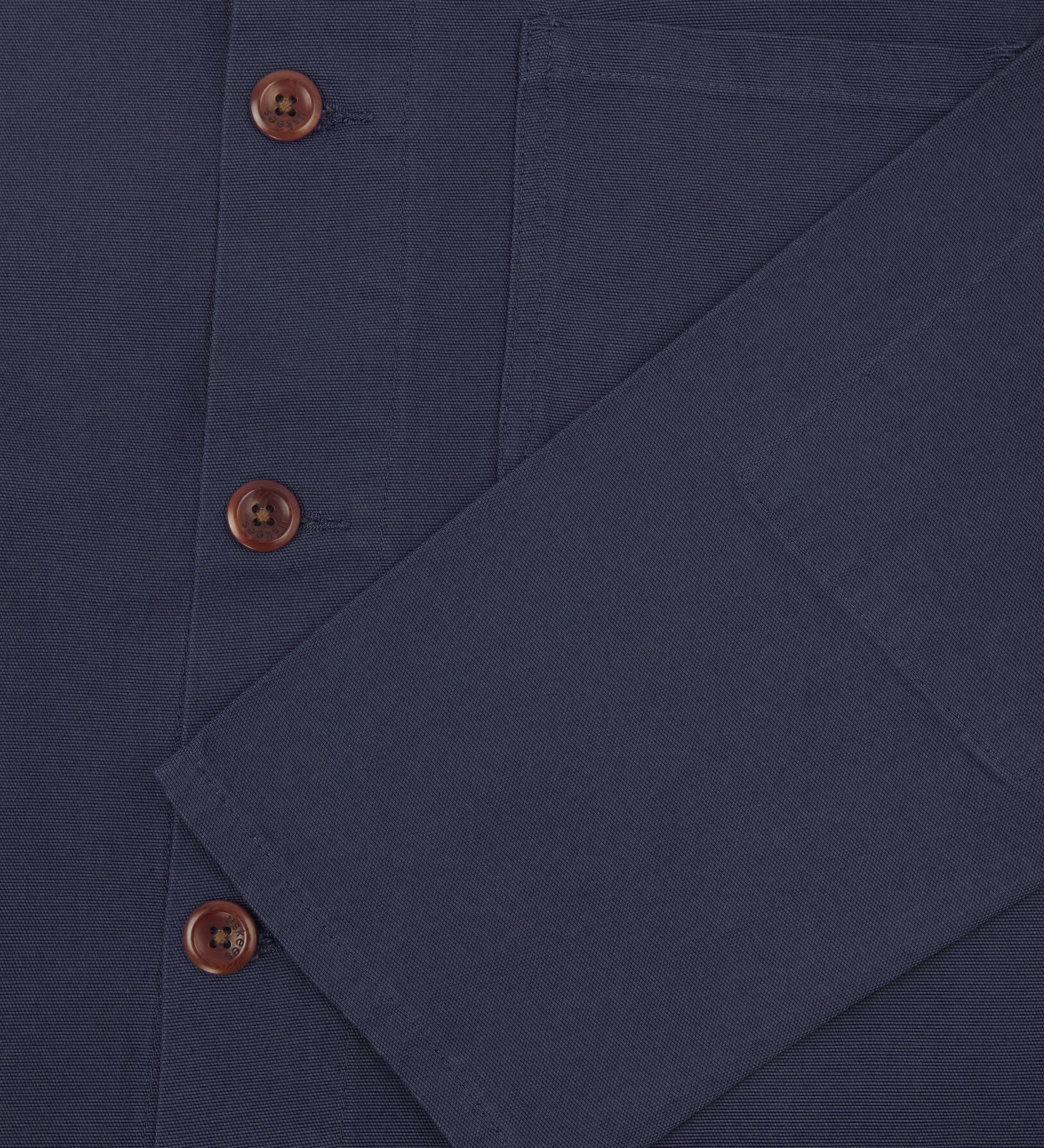 Closer view of mid section of midnight blue, buttoned organic cotton overshirt from Uskees. Focus on cuff, pockets and corozo buttons.